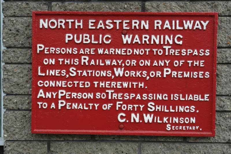 Red enamel North Eastern Railway public warning sign against trespass, penalty forty shillings.